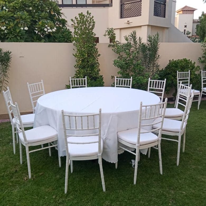 A round table with white chairs in a garden