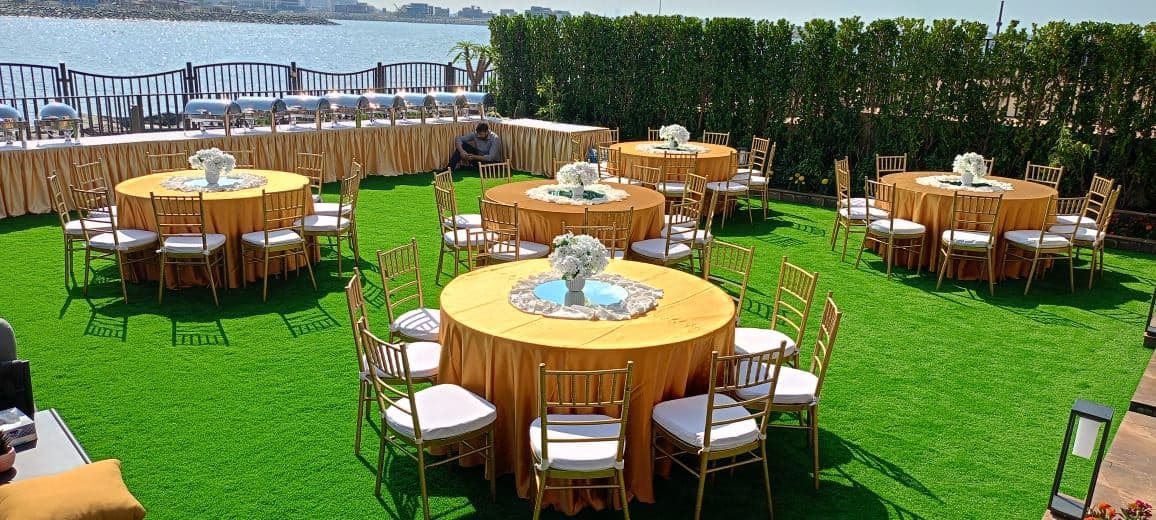 Round dining tables and chairs set on a lawn for an event