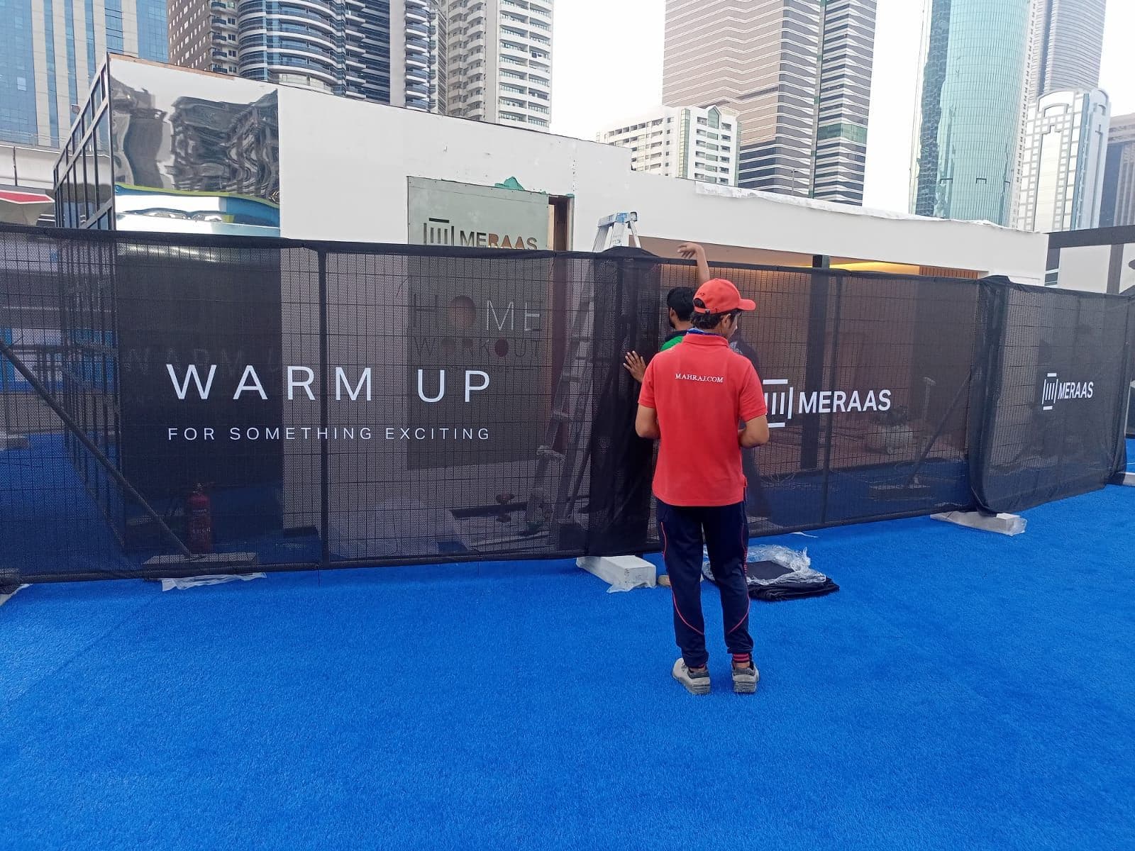 A team member installing printed fence wraps on site
