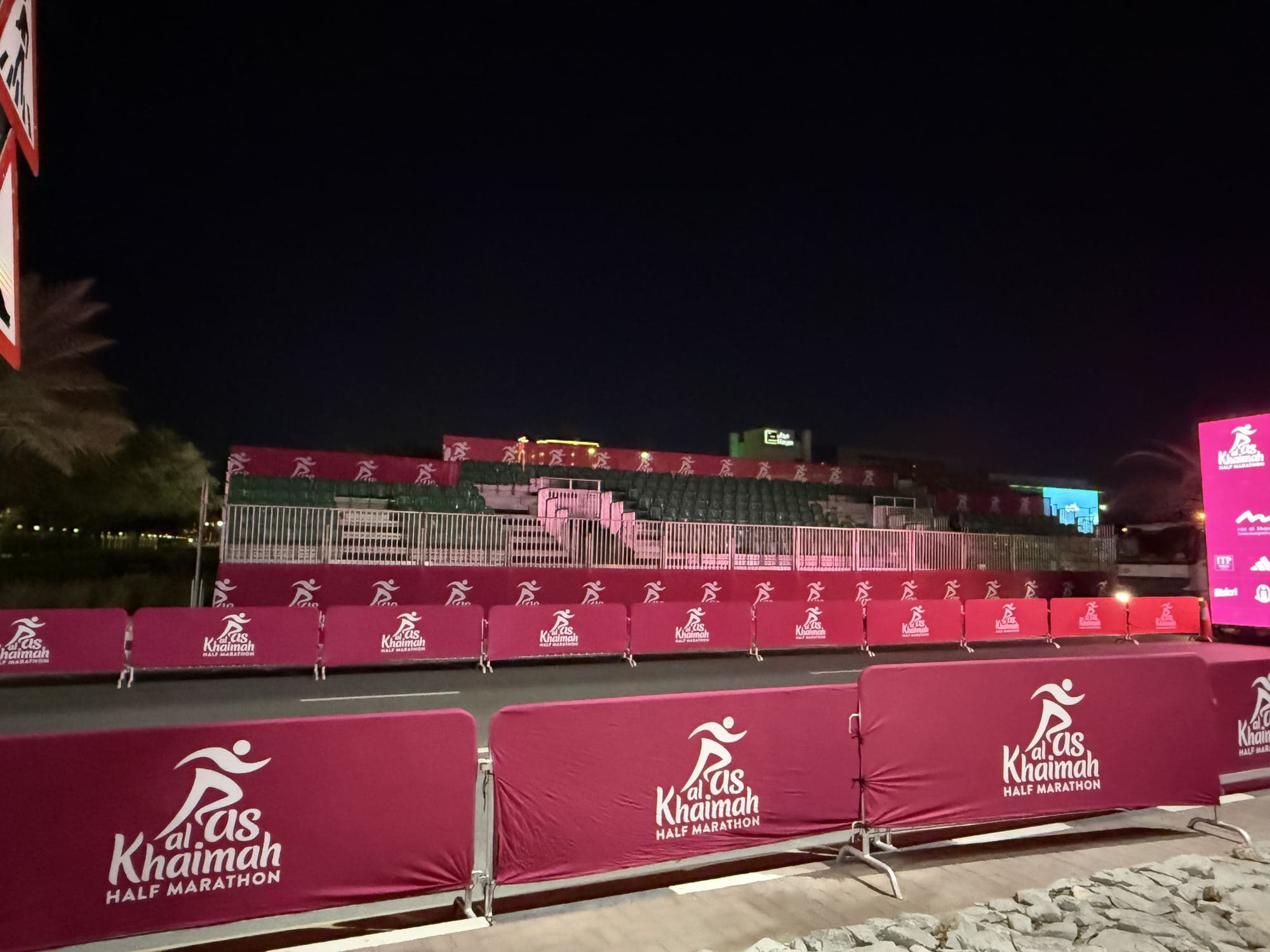 Rows of barriers with printed covers around a venue at night
